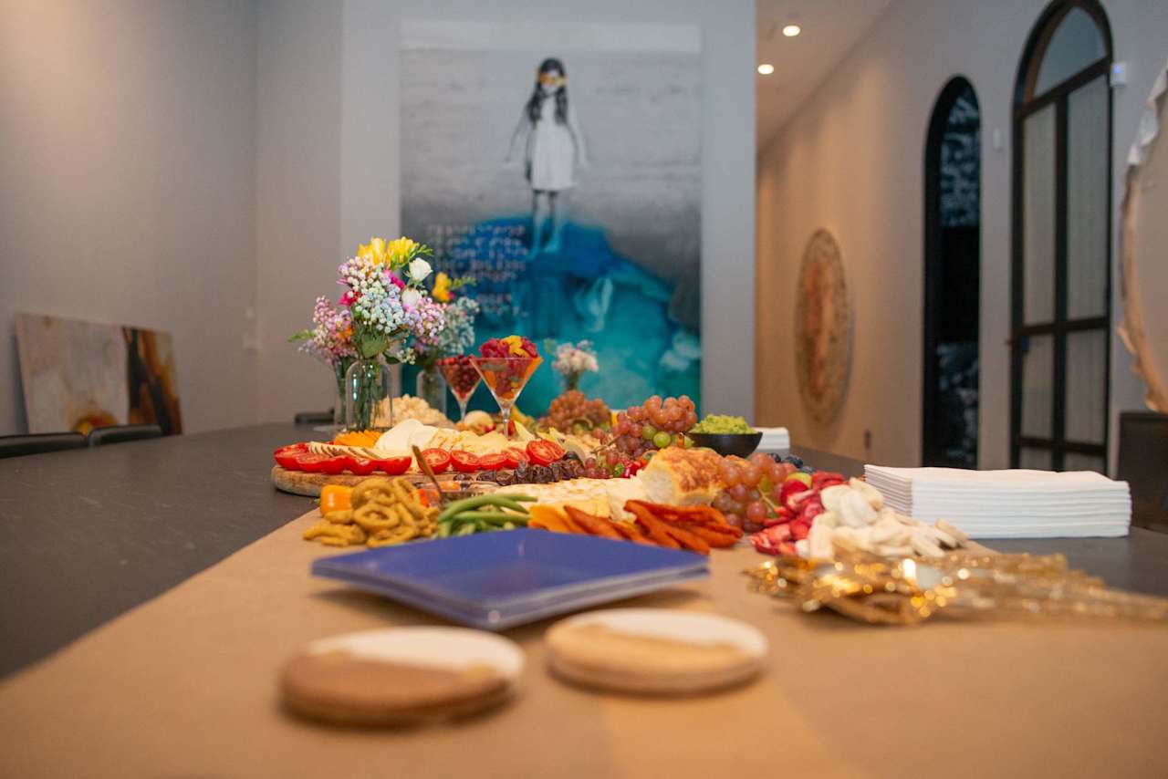 Event space with a buffet table, flower arrangements, artwork, and tall arched windows.