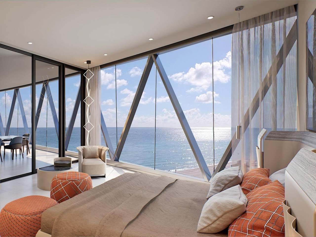 Bedroom with orange accent pillows and floor-to-ceiling windows overlooking the ocean.
