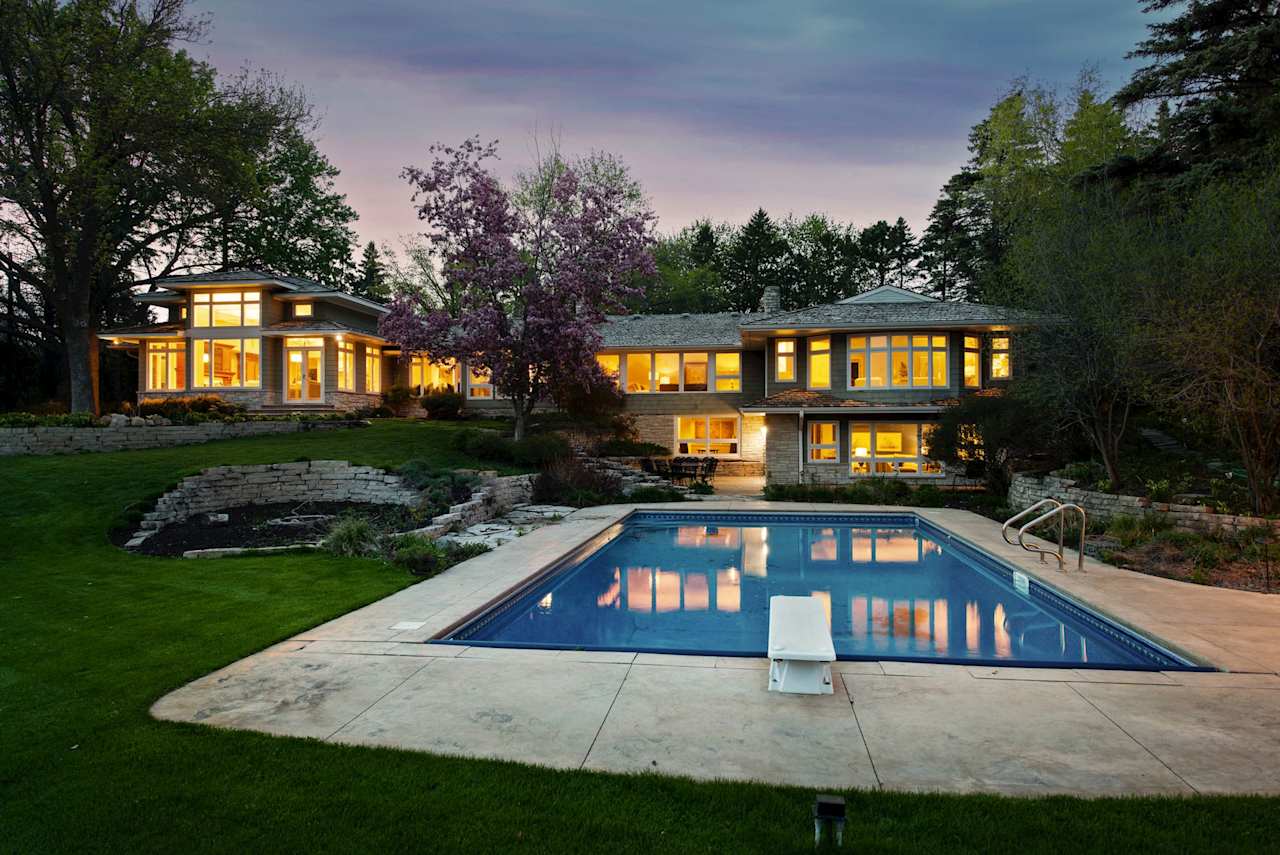 A two-story house with white exterior and black trim with a swimming pool in the backyard.