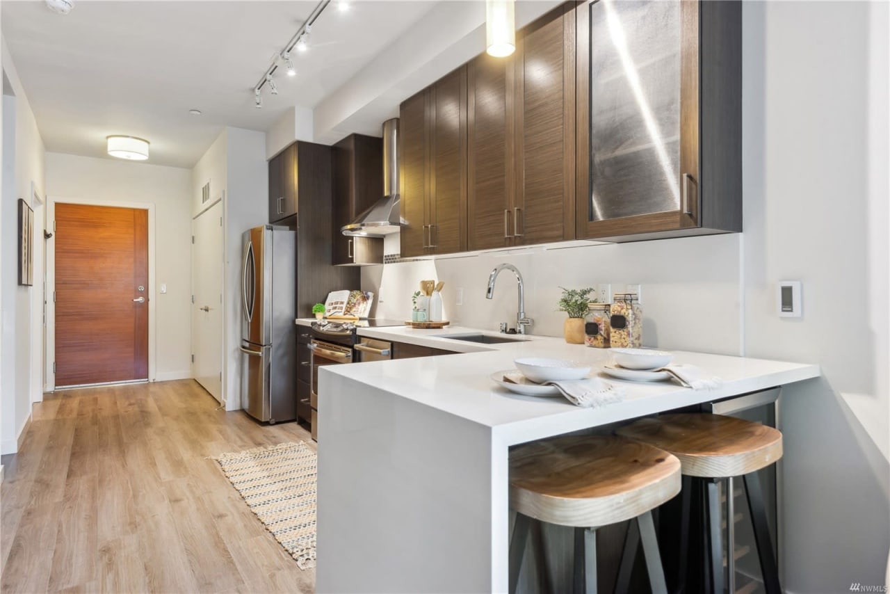 Compact and sleek condo kitchen with wood finishes and a minimalist bar setup, radiating modern charm.