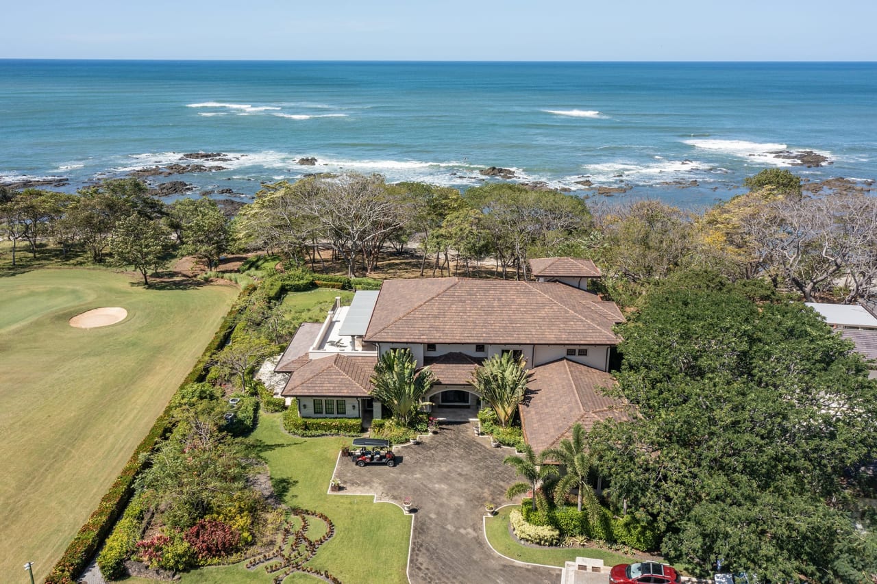 Lush green foliage surrounds the property. The mood is tranquil, and the colors are dominated by turquoise, green, and brown.