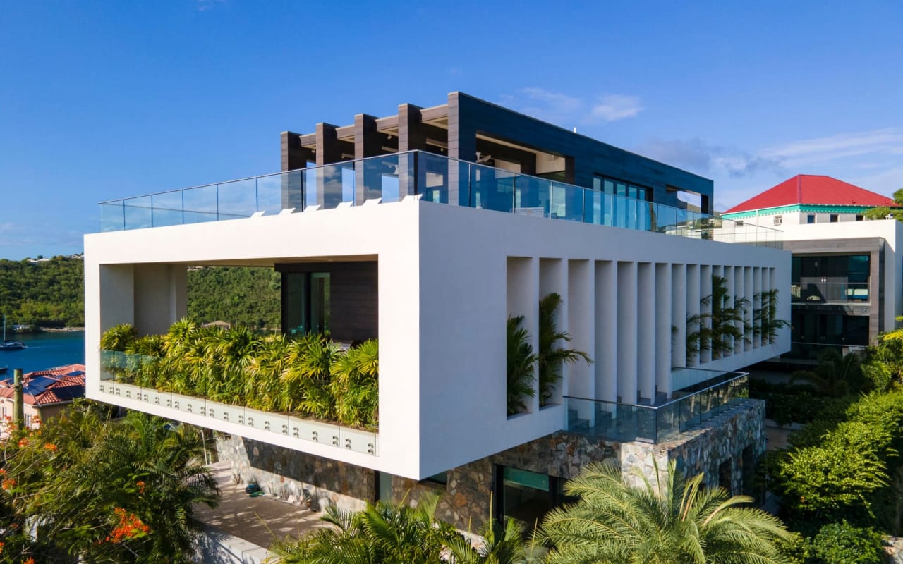 Aerial view of a modern villa with a swimming pool, set amidst lush greenery on a tropical island