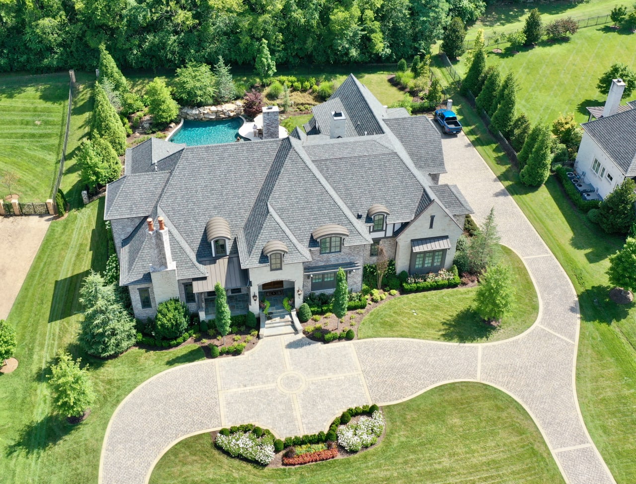 An aerial view of a large house with a red tile roof and a swimming pool in the backyard.