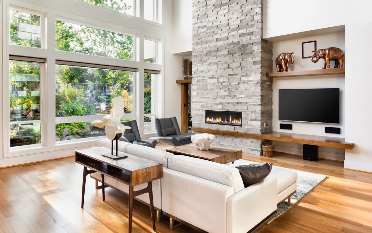 A living room with a white couch, a brick fireplace, and a white flat-screen television.