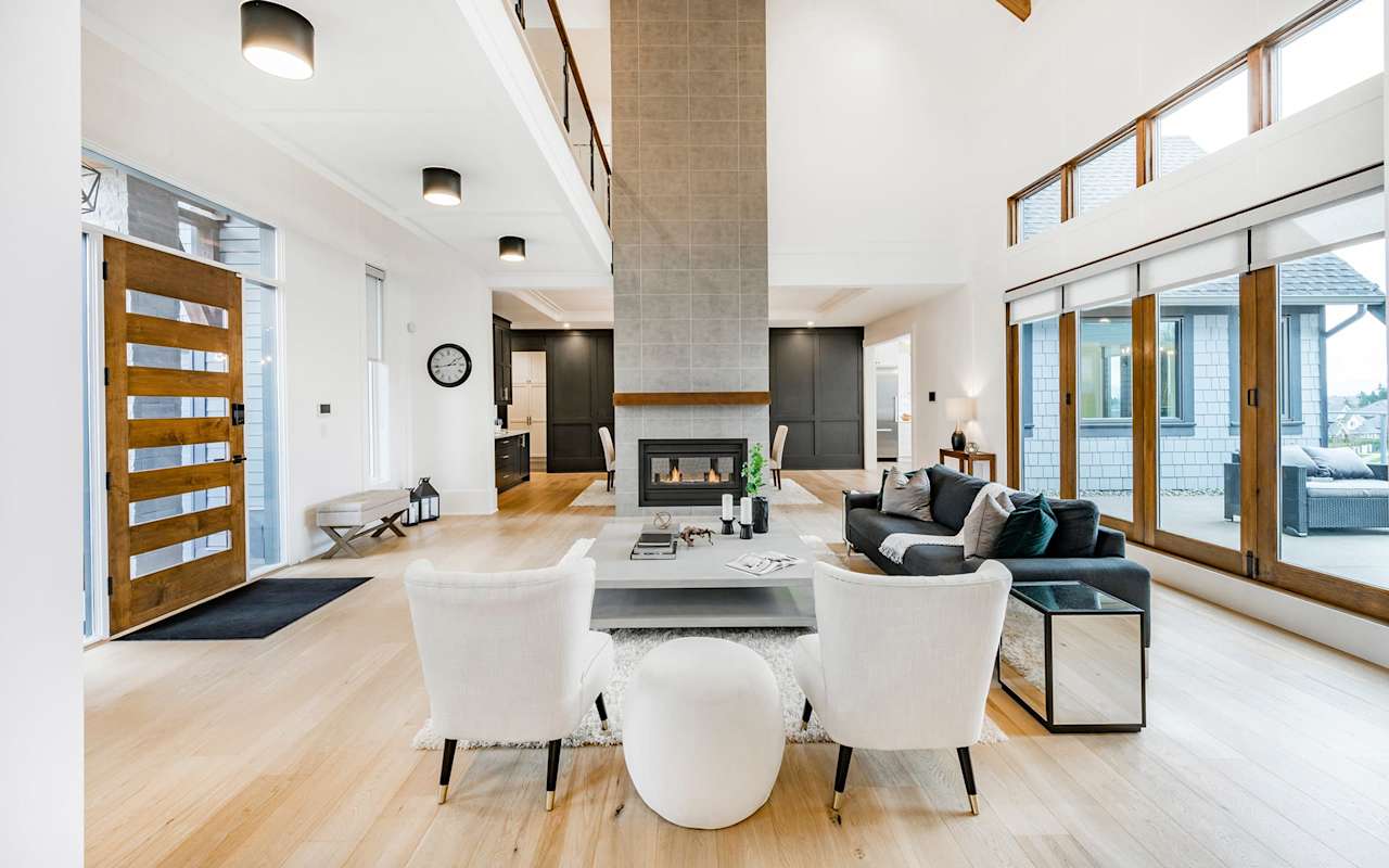 A spacious living room with a fireplace, couch, armchair, and rug