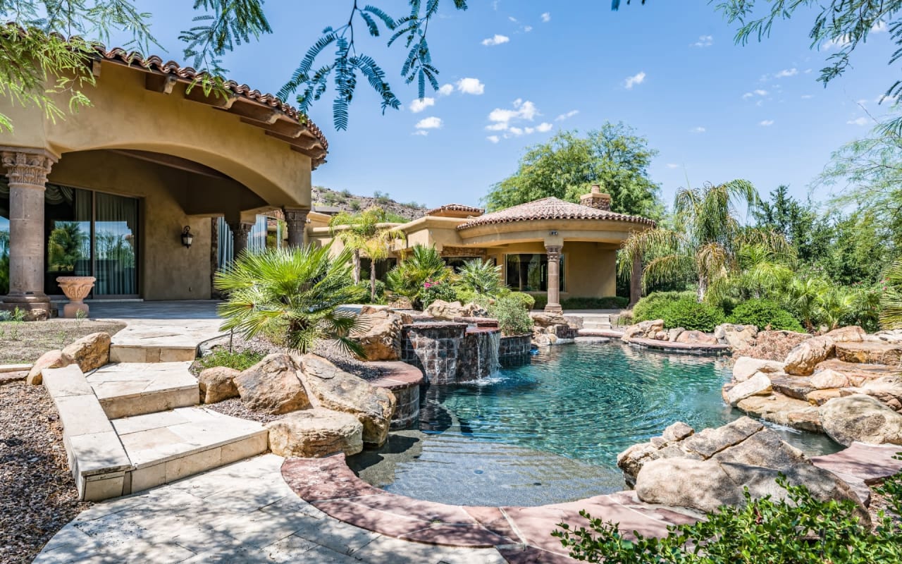 A beautiful backyard oasis with a swimming pool and waterfall
