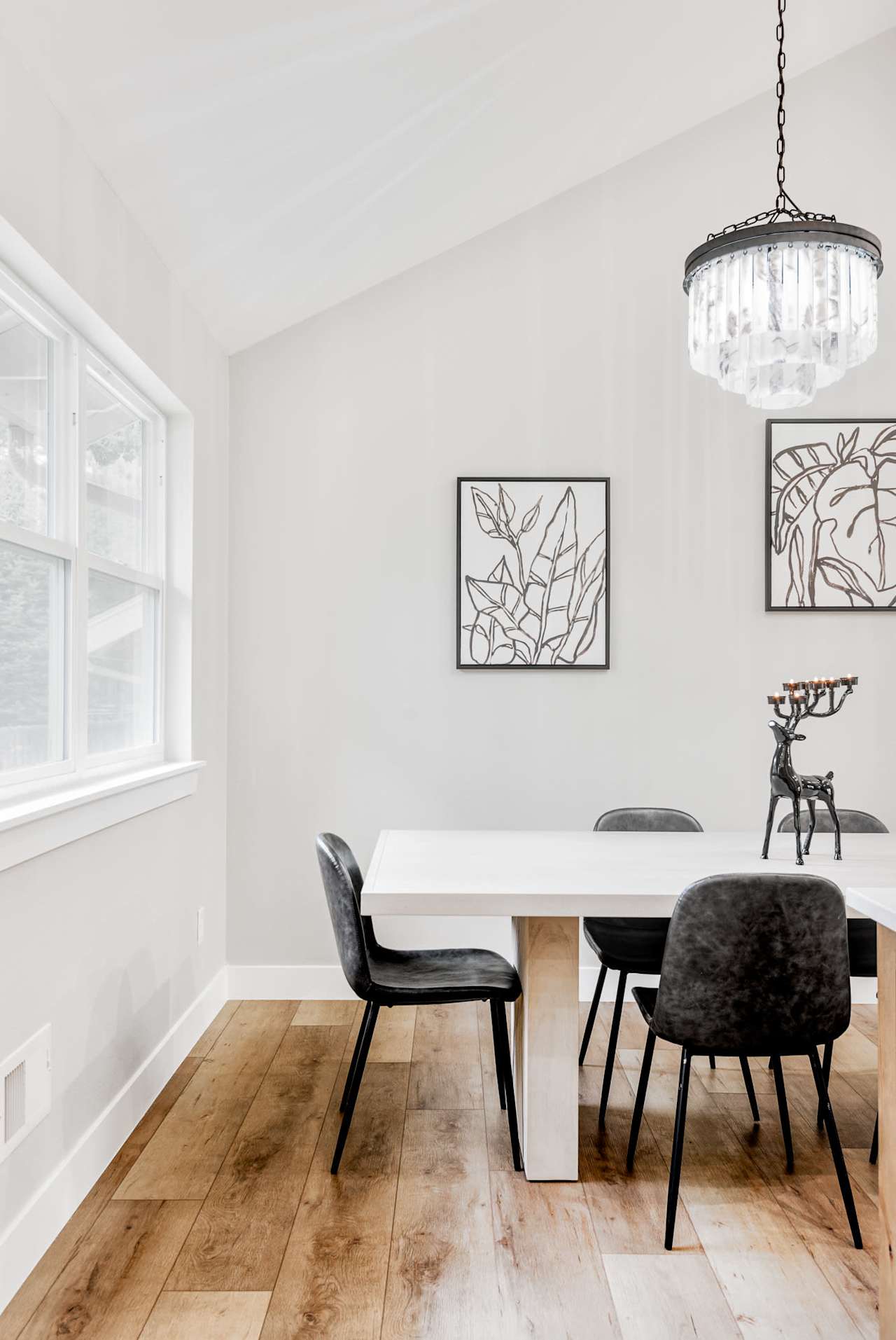 A white dining table and chairs in a room with hardwood floors and a chandelier