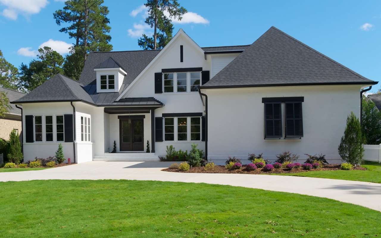 Modern luxury home with clean lines, a white facade, and lush landscaping embodying upscale suburban living.