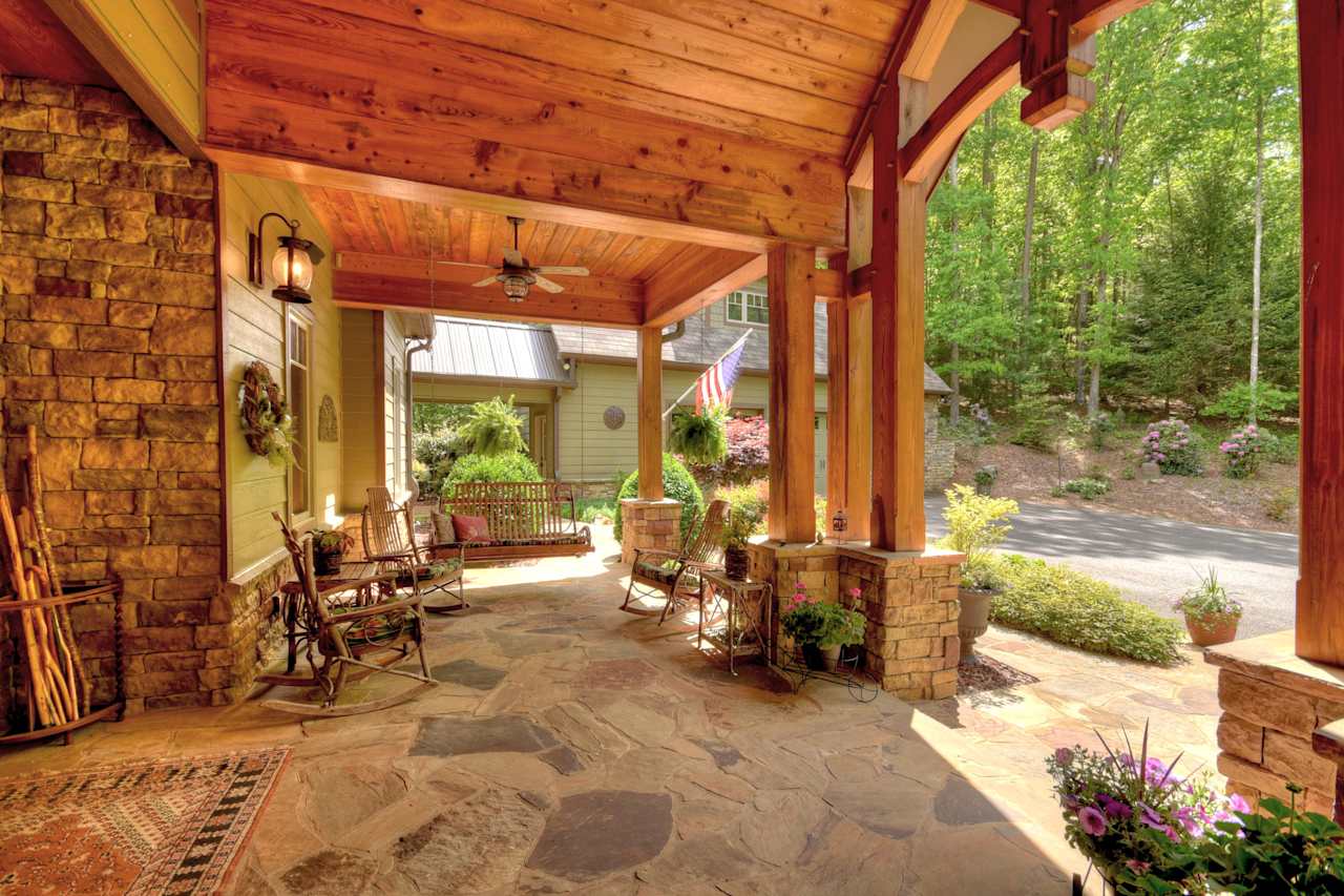 A covered porch with two wooden rocking chairs and a white American flag hanging on the wall