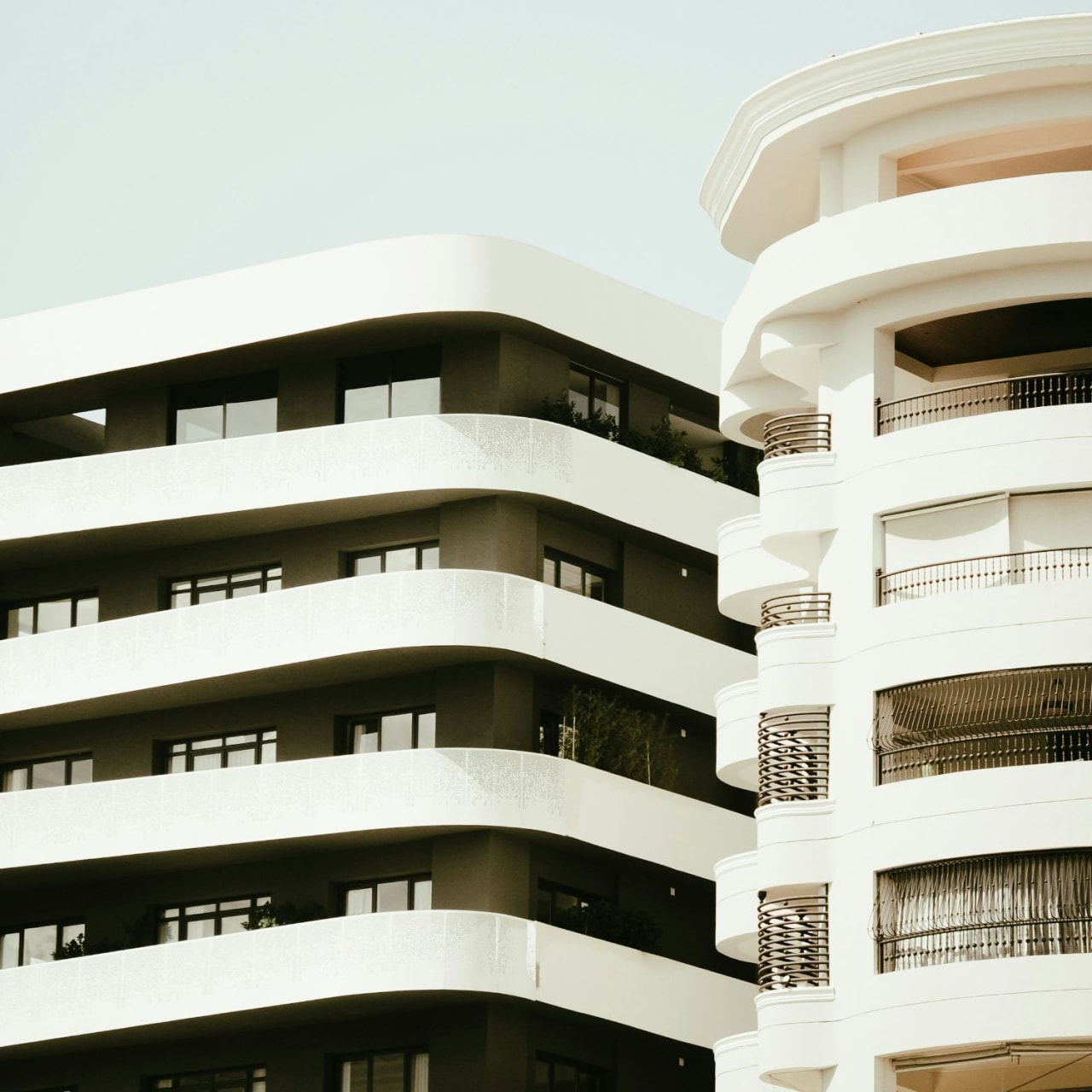 A close-up of two contemporary skyscrapers featuring multiple stories, numerous windows, and balconies with glass railings.