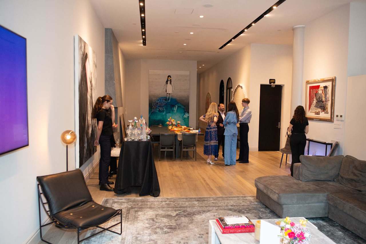 Art-filled furnished lounge with guests gathered around a dining table.