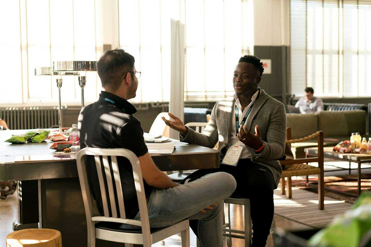 Two men engaged in conversation while seated at a table, sharing ideas and enjoying each other's company.