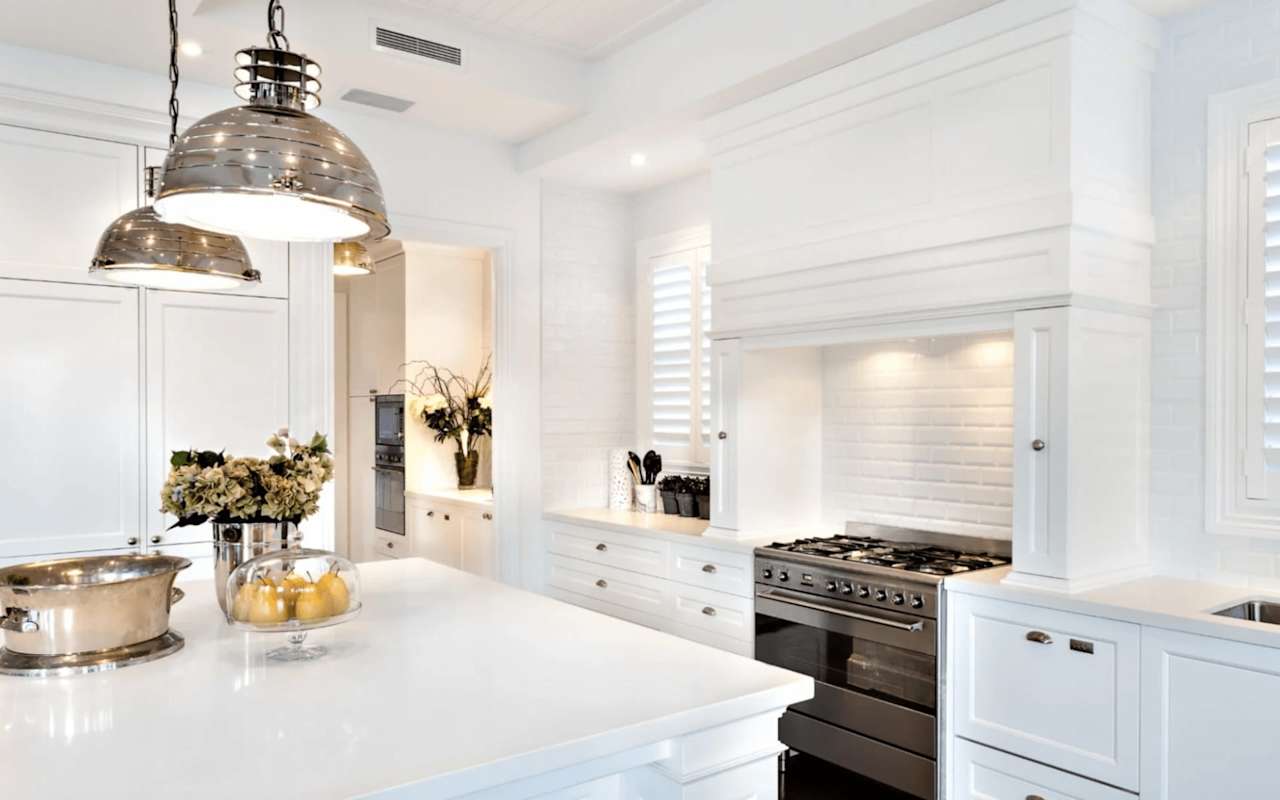 A modern kitchen with white cabinets, countertops, and backsplash.