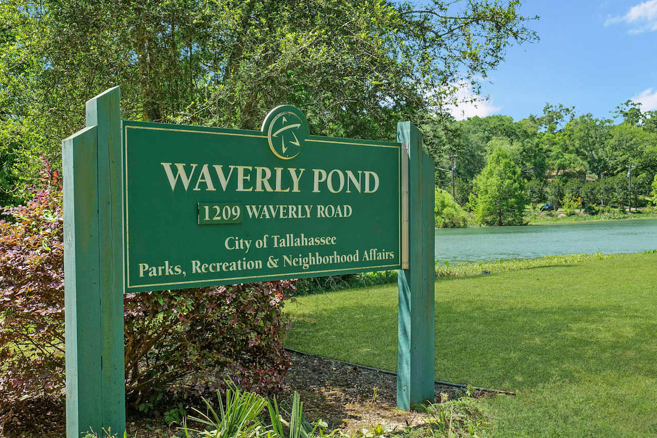  An image of a green sign for "Waverly Pond" which likely is a park or neighborhood area, with trees and a pond in the background.