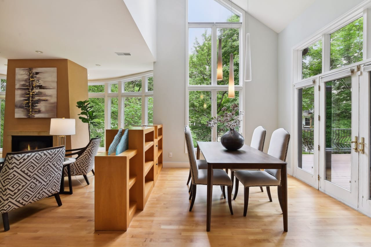 A dining room with a wooden table and a vase with flowers in the center.