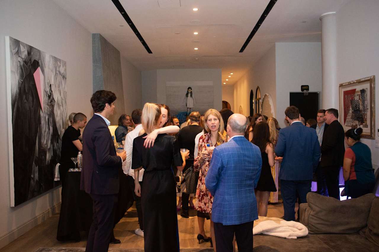 Guests mingle at a reception in a modern lounge with large abstract artwork.