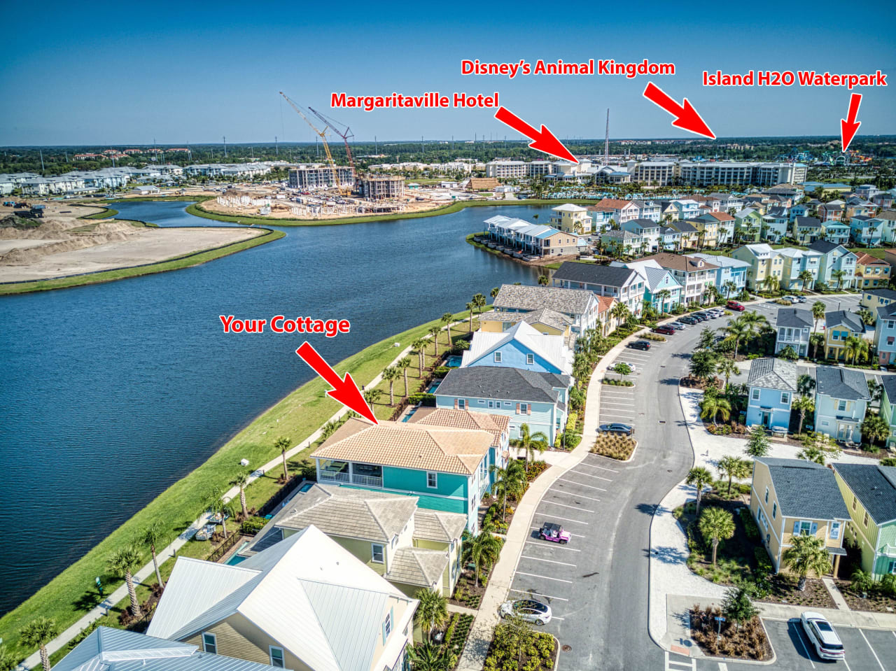 An aerial view of a vacation resort with a variety of buildings, including colorful cottages, a large water park with slides and pools, and a Disney-themed park