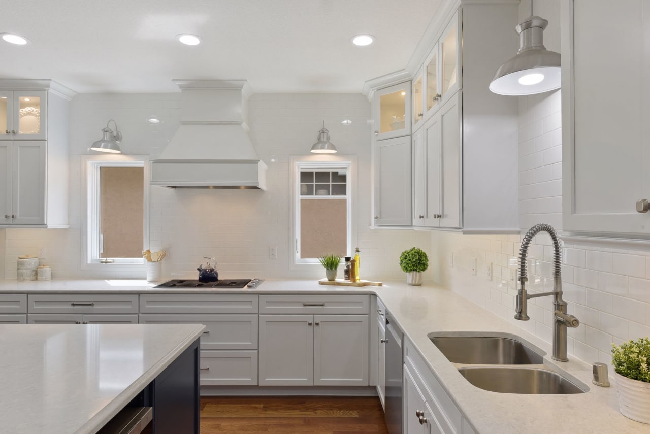 A clean and well-lit kitchen with white cabinets and a stainless steel sink.