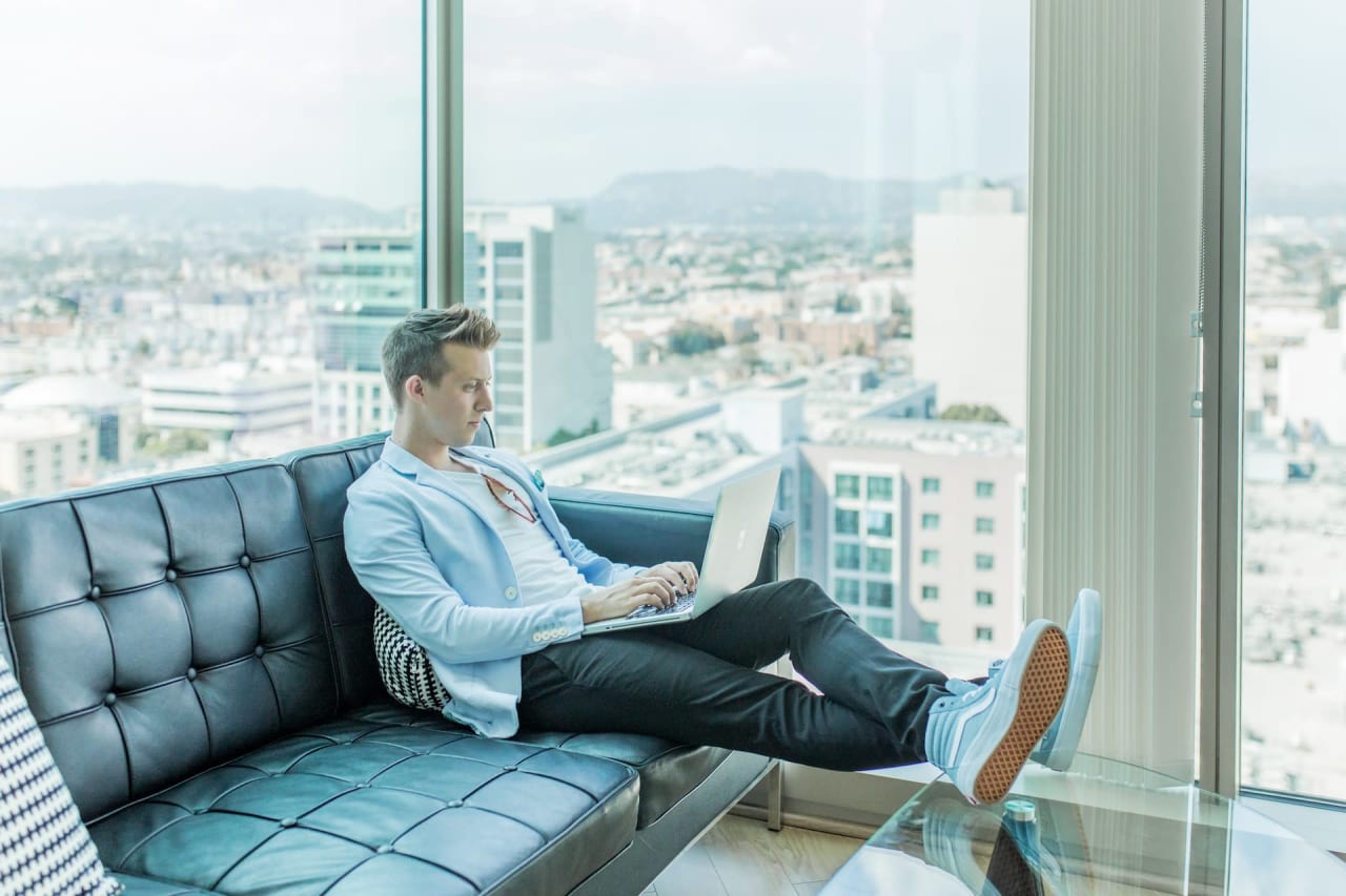 A realtor on a couch with a laptop embracing the role of real estate agents in the digital age