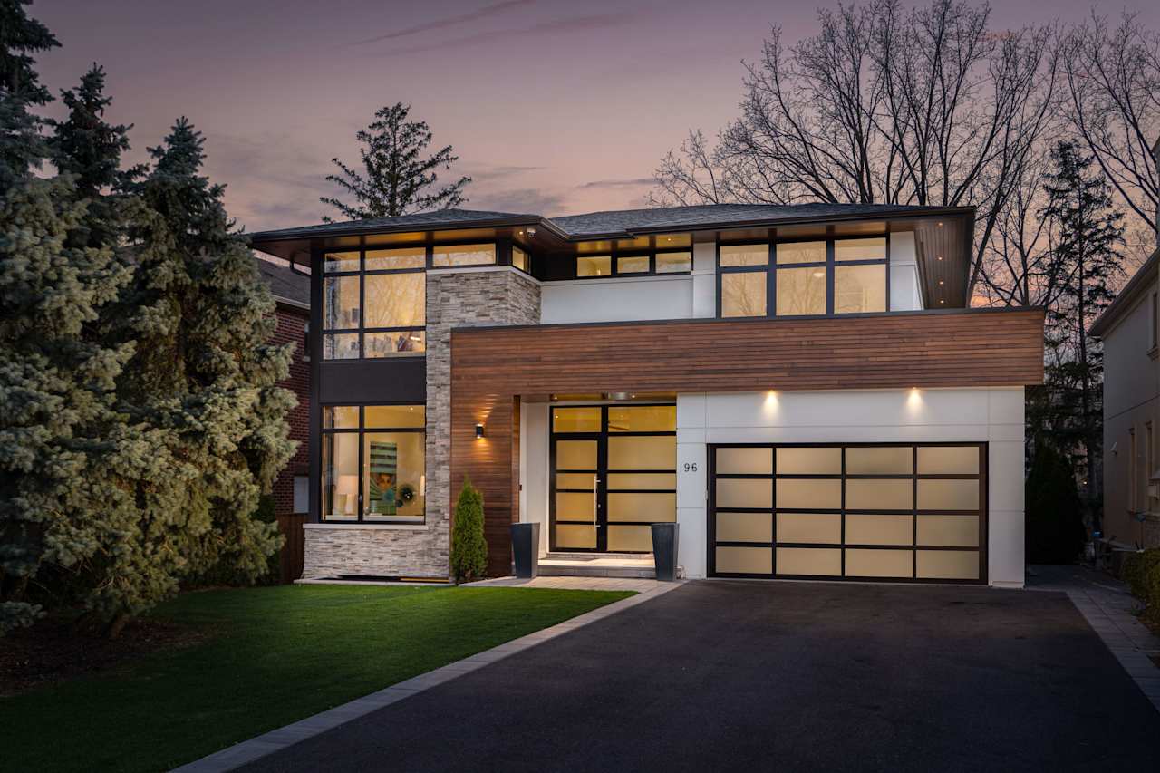 sleek and stylish modern house with large windows and with a two-car garage and a driveway