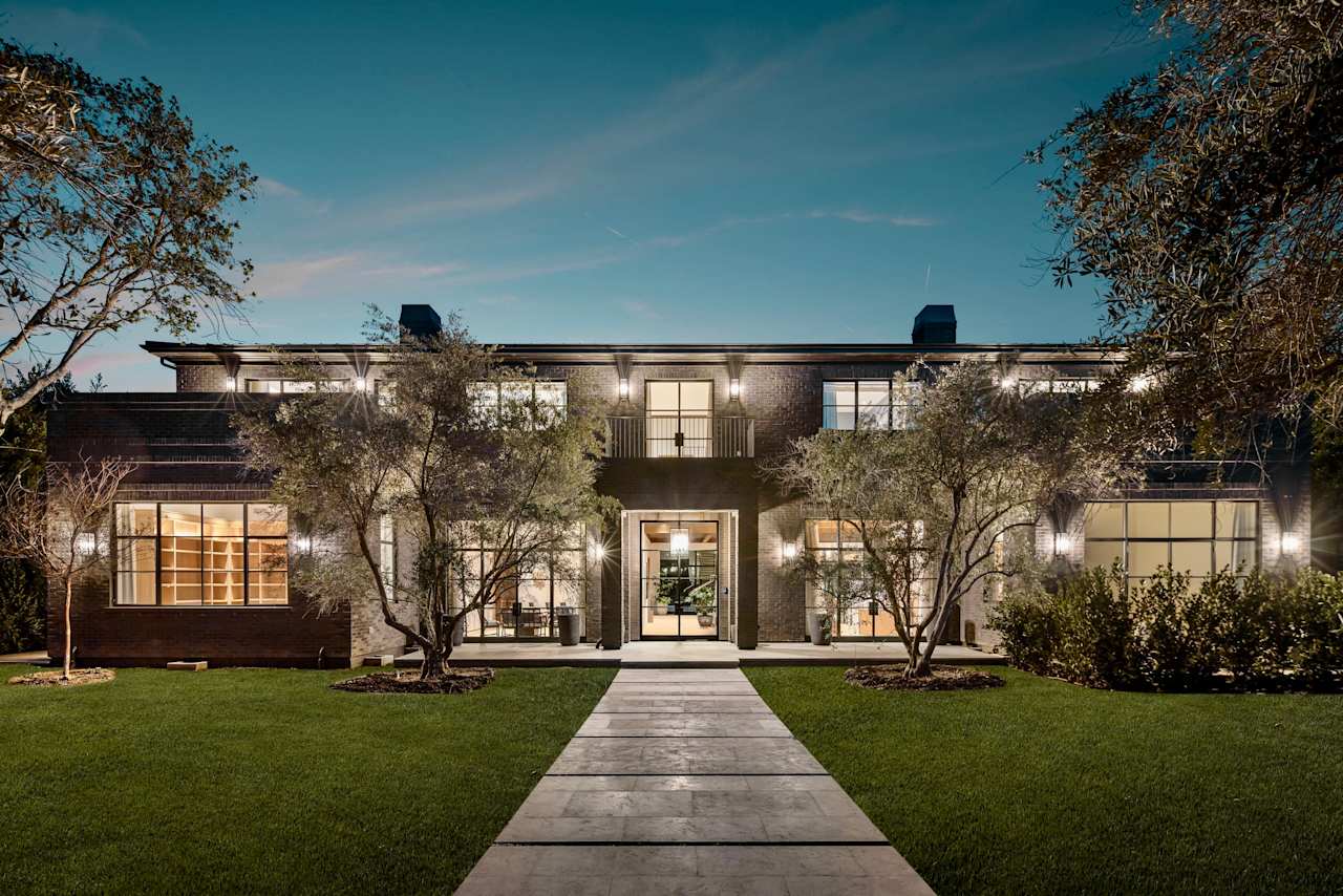 A stone pathway leads to a contemporary house with a minimalist design