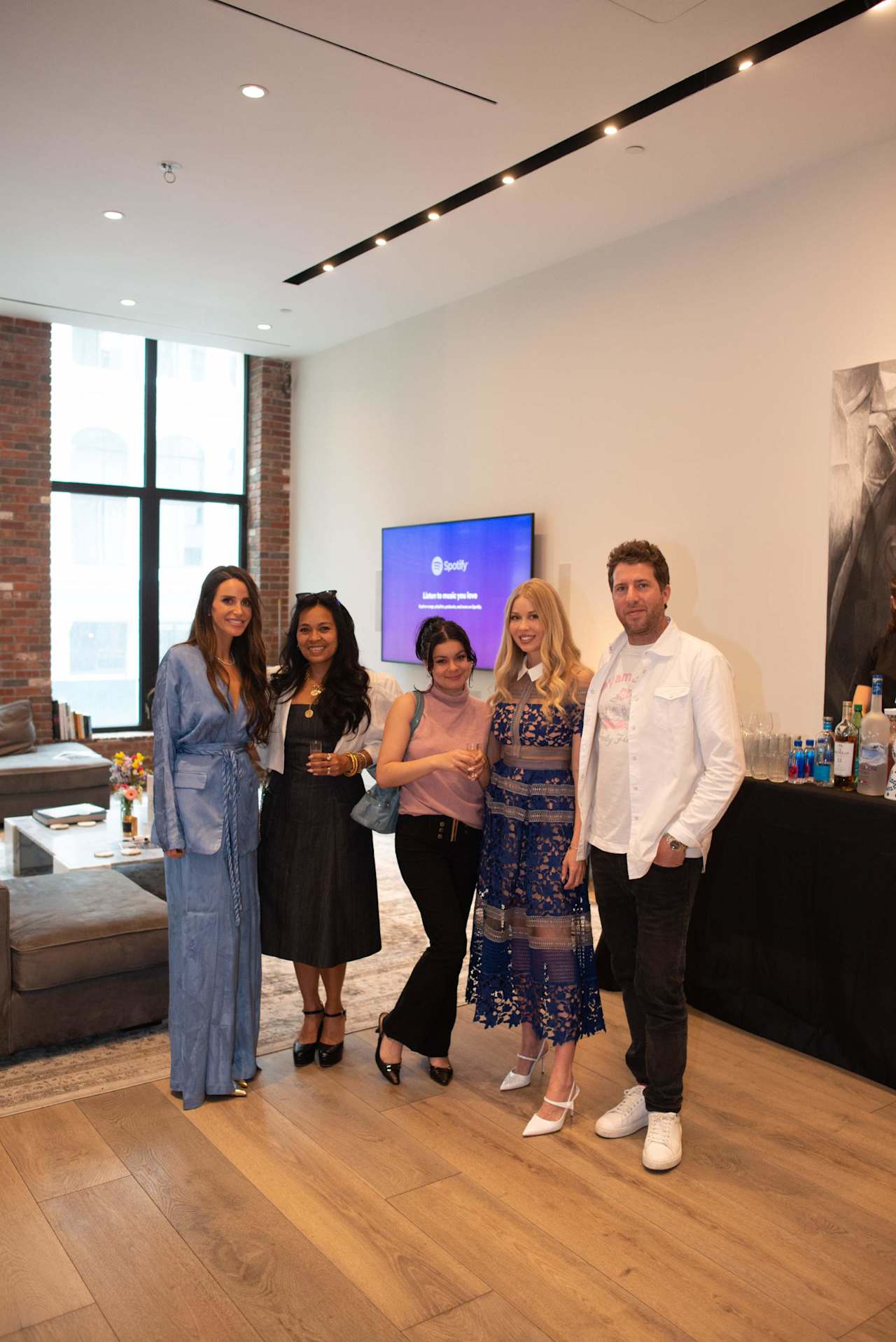 Five adults pose together at a gathering in a modern office lounge.