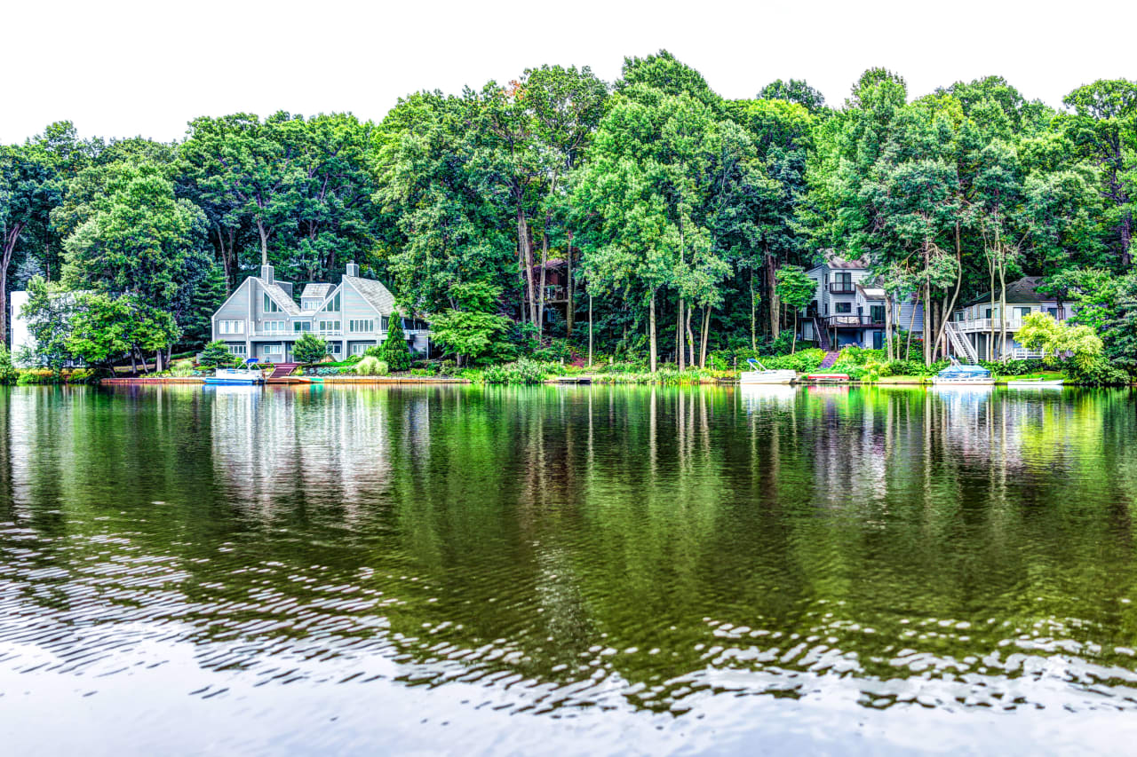 Lake scene with several houses interspersed into the trees along the lake bank