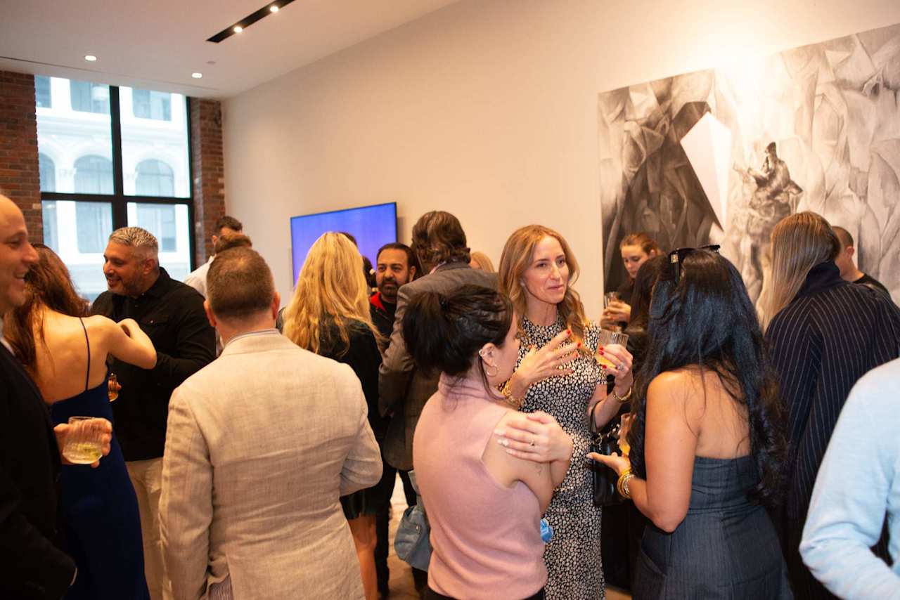 Guests mingle at a networking reception in a bright room with large windows and abstract wall art.