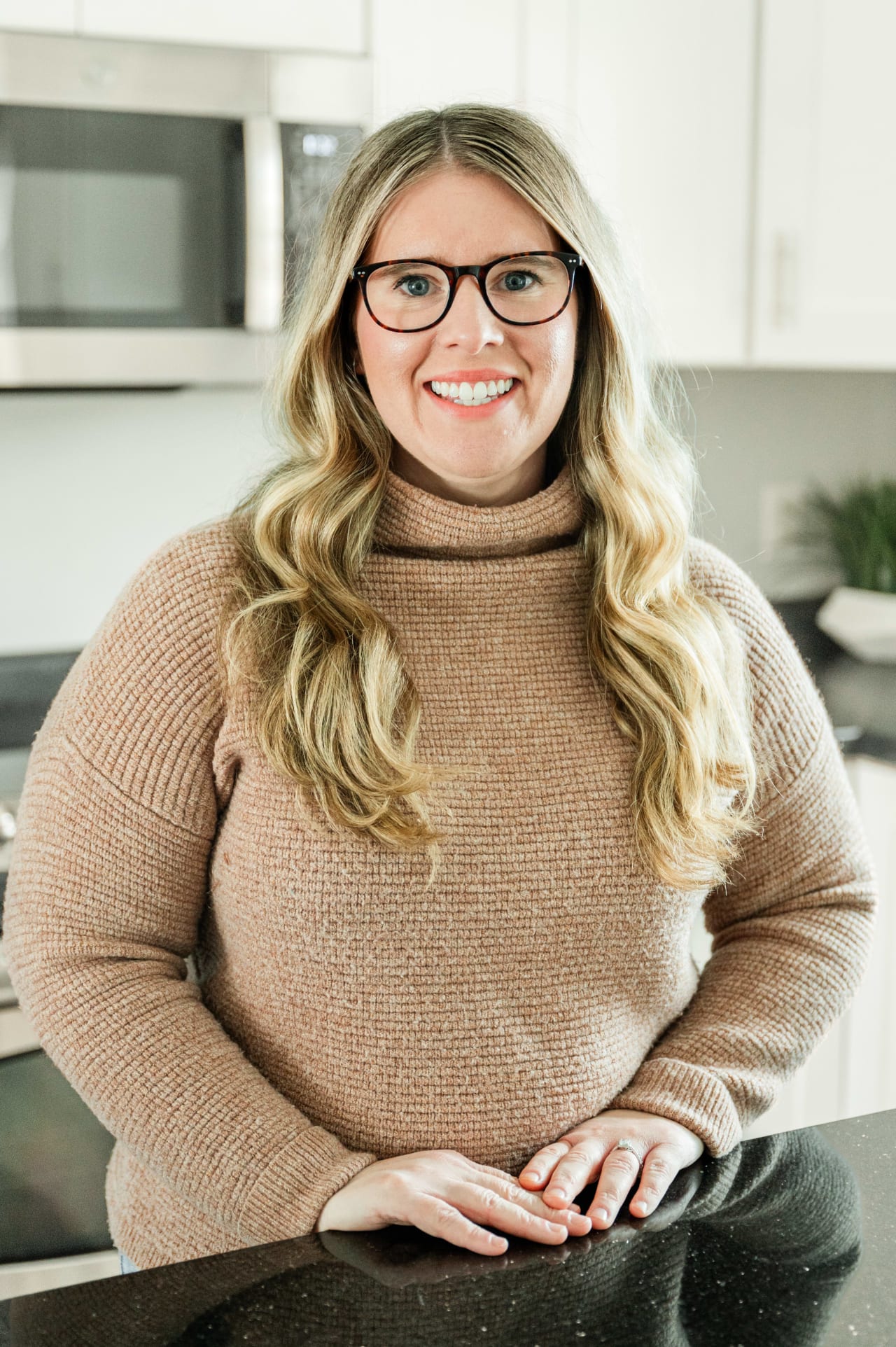 Stephanie Knutson, a real estate agent from the Insiders Realty team, wearing glasses, is standing in a kitchen.