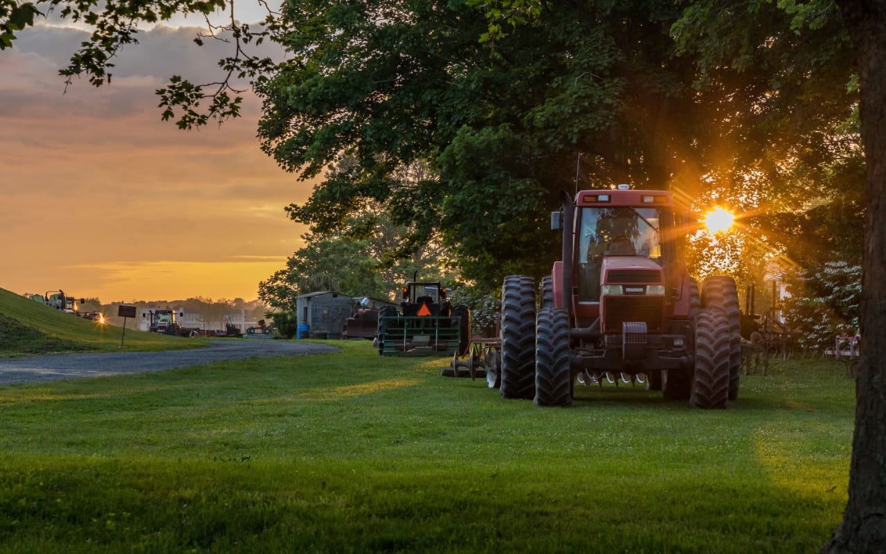 A tractor parked in a grassy field at sunset