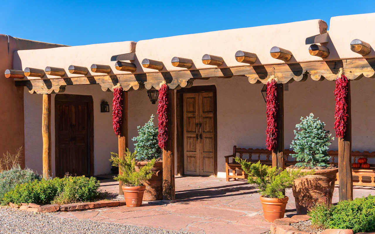 A patio with a wooden pergola covered in red chili peppers.