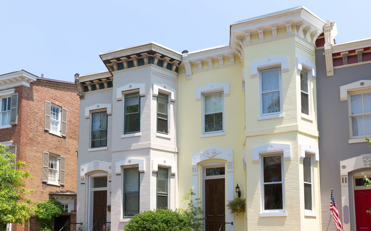 A vibrant row of two-story houses with a flag on a sunny day.