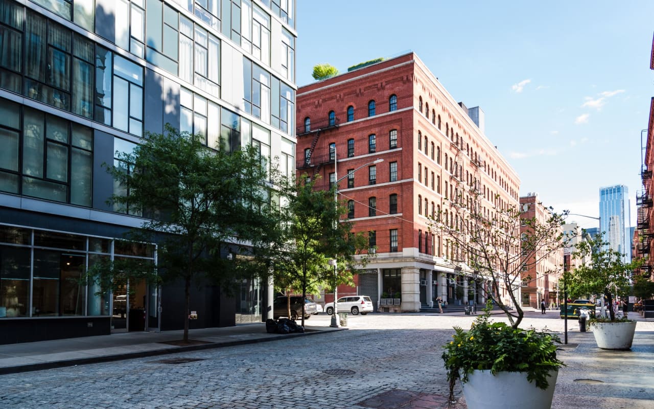 Cobblestone street in Tribeca, New York City with a red brick building in the background.