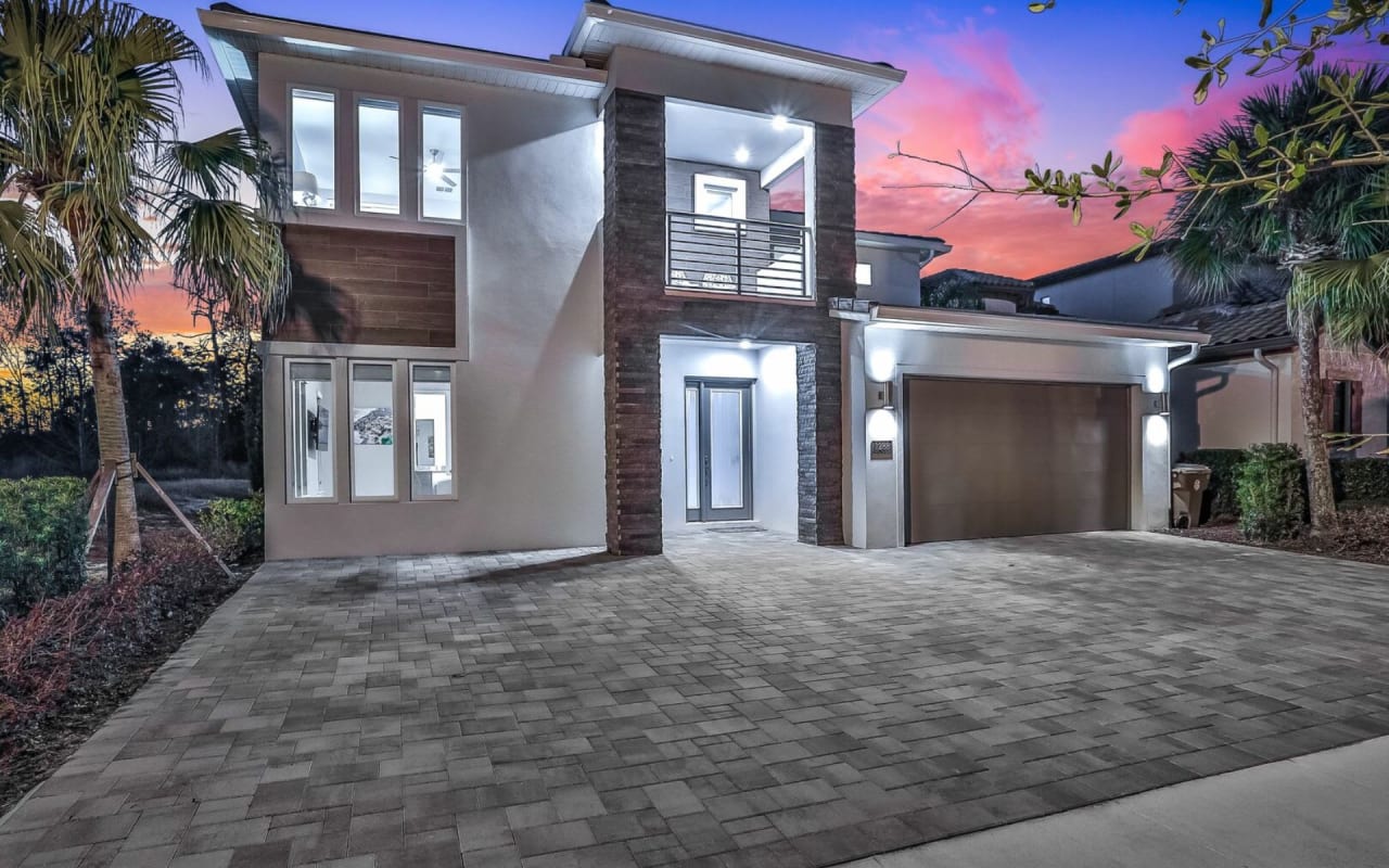 A large white house with a black garage door and a long brick driveway.