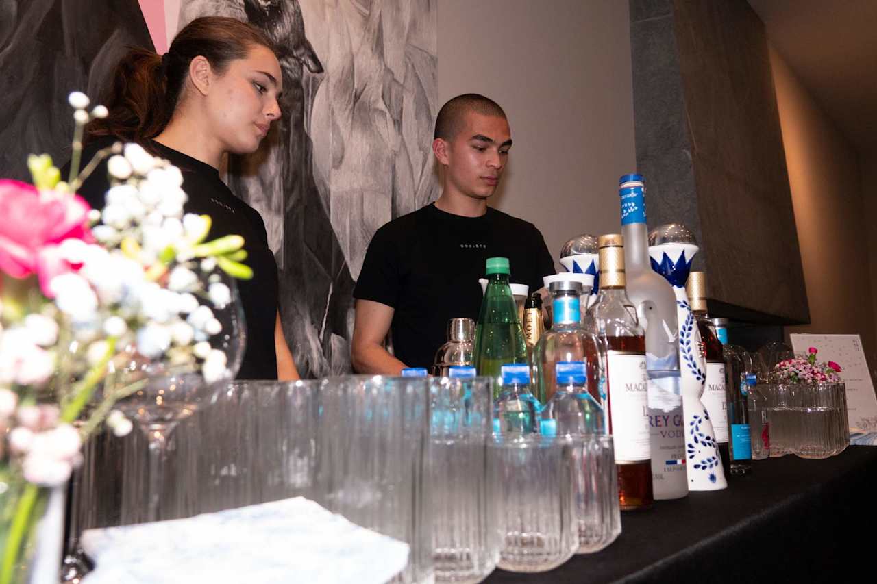 Two Societe staff members behind an event bar lined with bottles and glassware.
