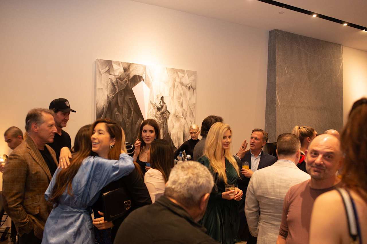 Guests mingle at an indoor event beneath large abstract wall art.