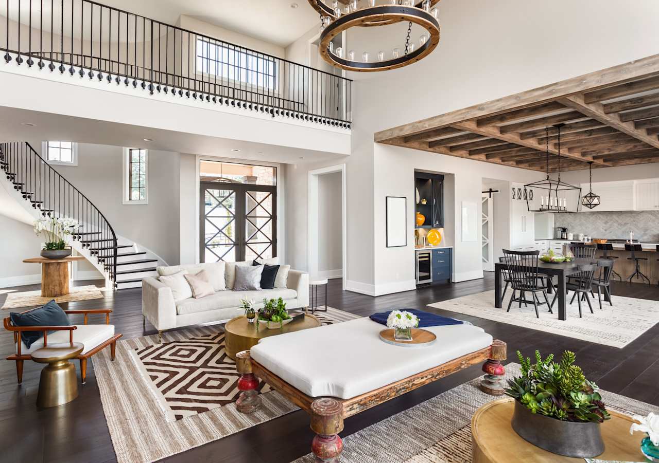 A living room with a white couch, chairs, and coffee table. There is a chandelier hanging from the ceiling.