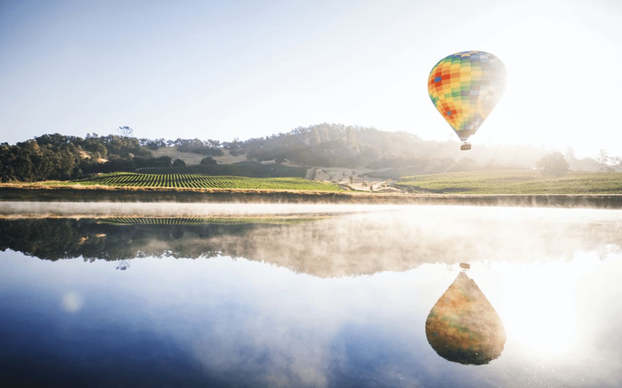 colorful hot air balloon with water reflection in the Napa vineyard property