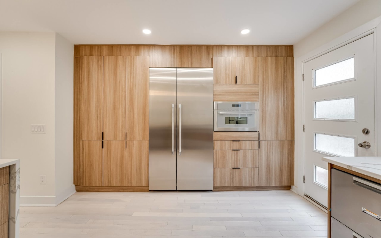 Modern kitchen with light wood cabinetry, stainless steel appliances, and minimalistic design.