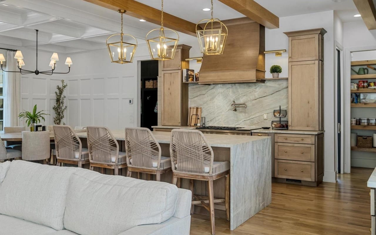 A kitchen with a stove and an island with four chairs around it.