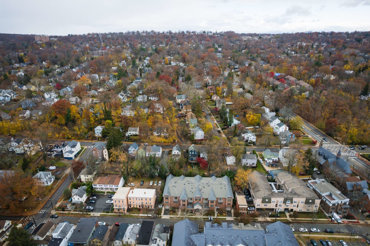 An aerial view of a suburban neighborhood in New Jersey during autumn, showing single-family homes with driveways and yards.