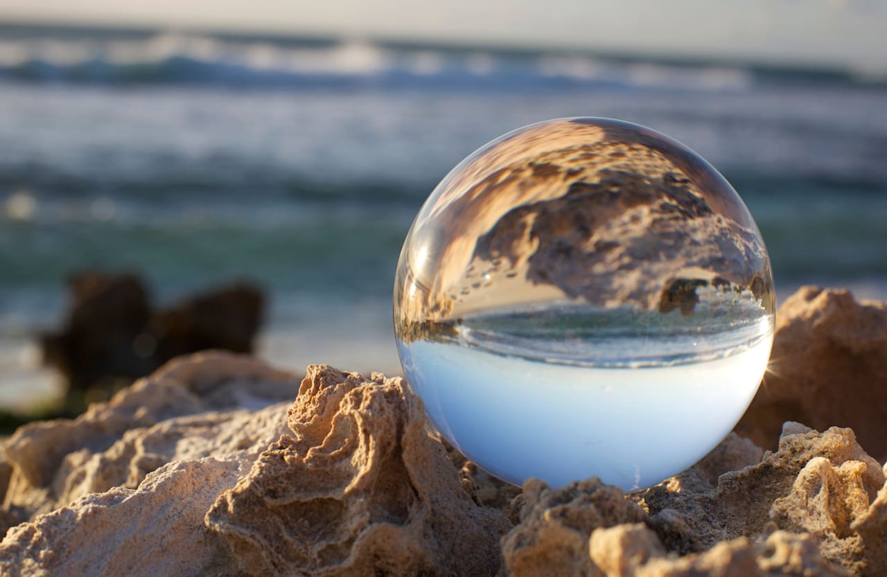 crystal ball on beach sand with ocean background