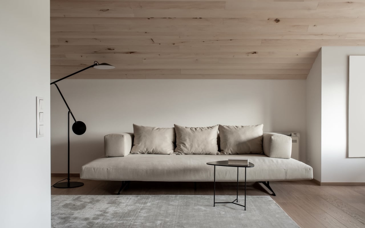 A living room with a beige couch, a wooden coffee table, and a floor lamp with a black shade.