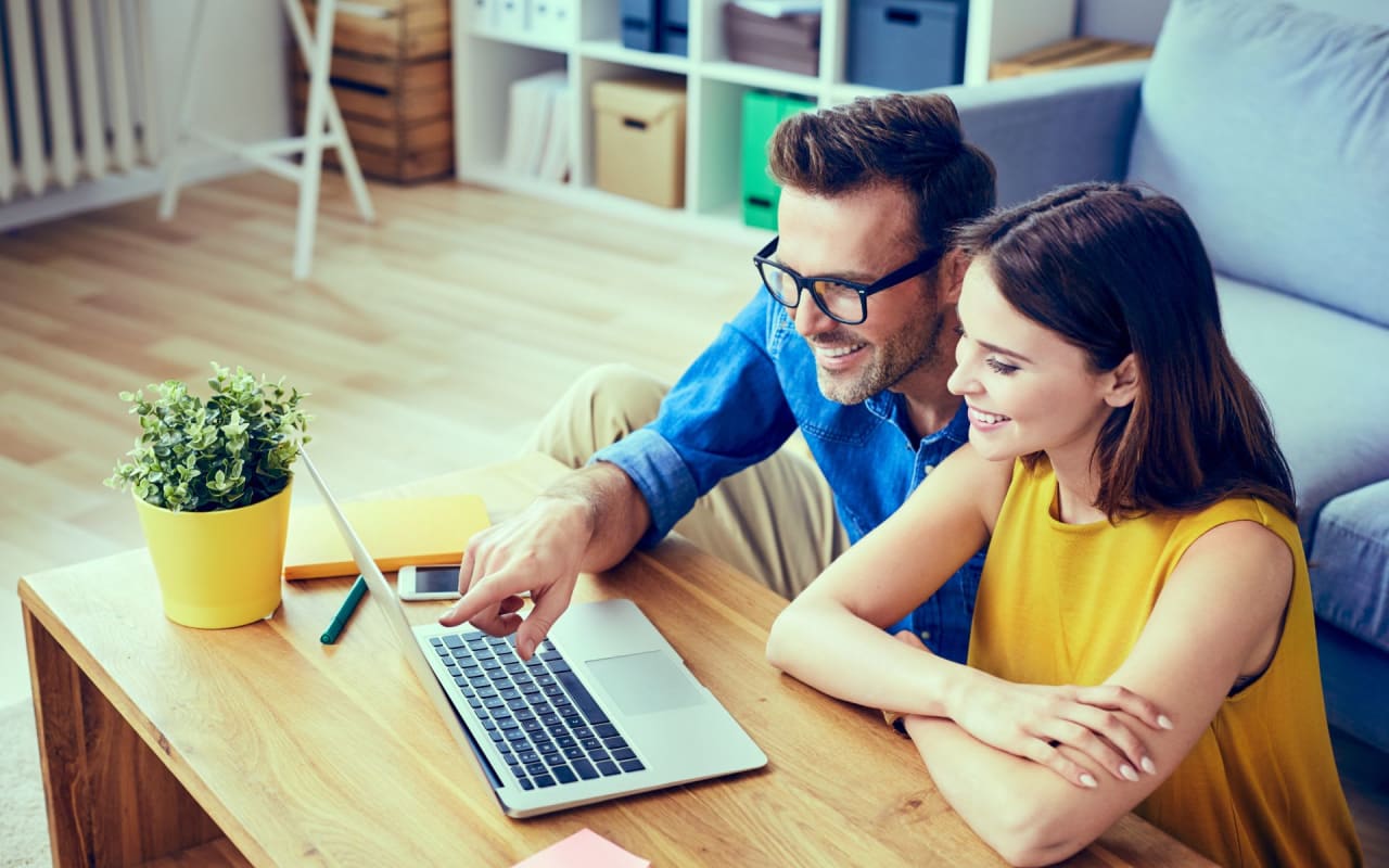 Five secrets about virtual tours that you must know. Male and female on the floor in front of couch viewing laptop screen on coffee table