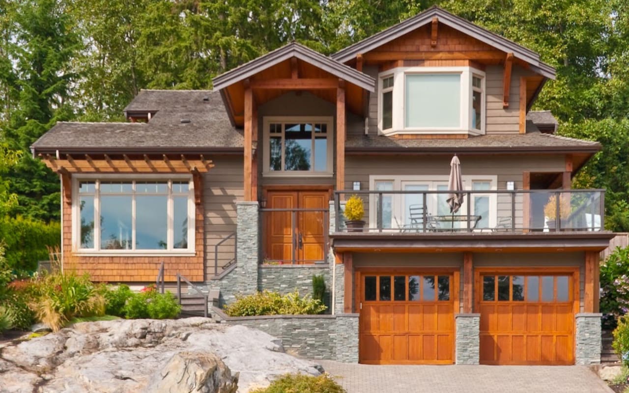 A photo of a large house with two garages and a balcony.