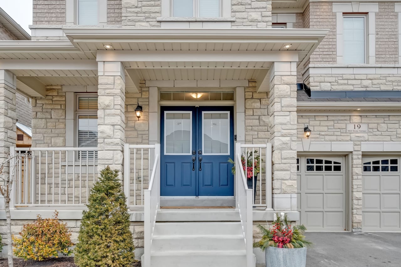 A suburban house with a bright blue front door and a large brick porch.