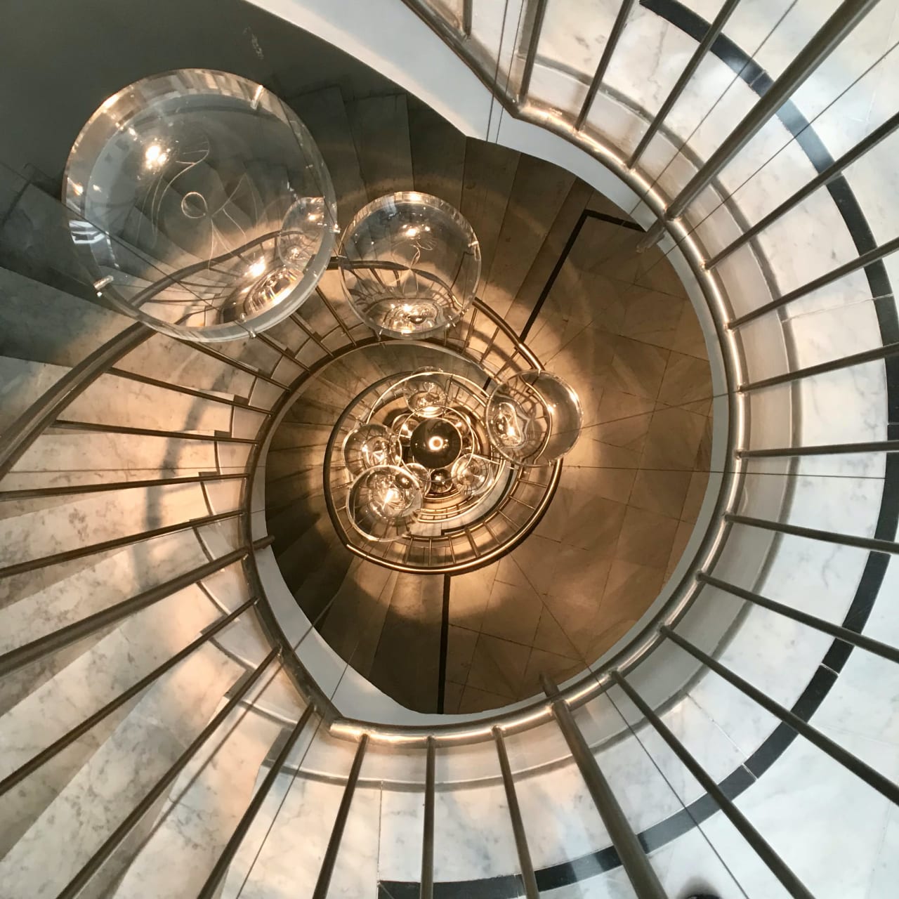 A spiral staircase with a chandelier in the center.