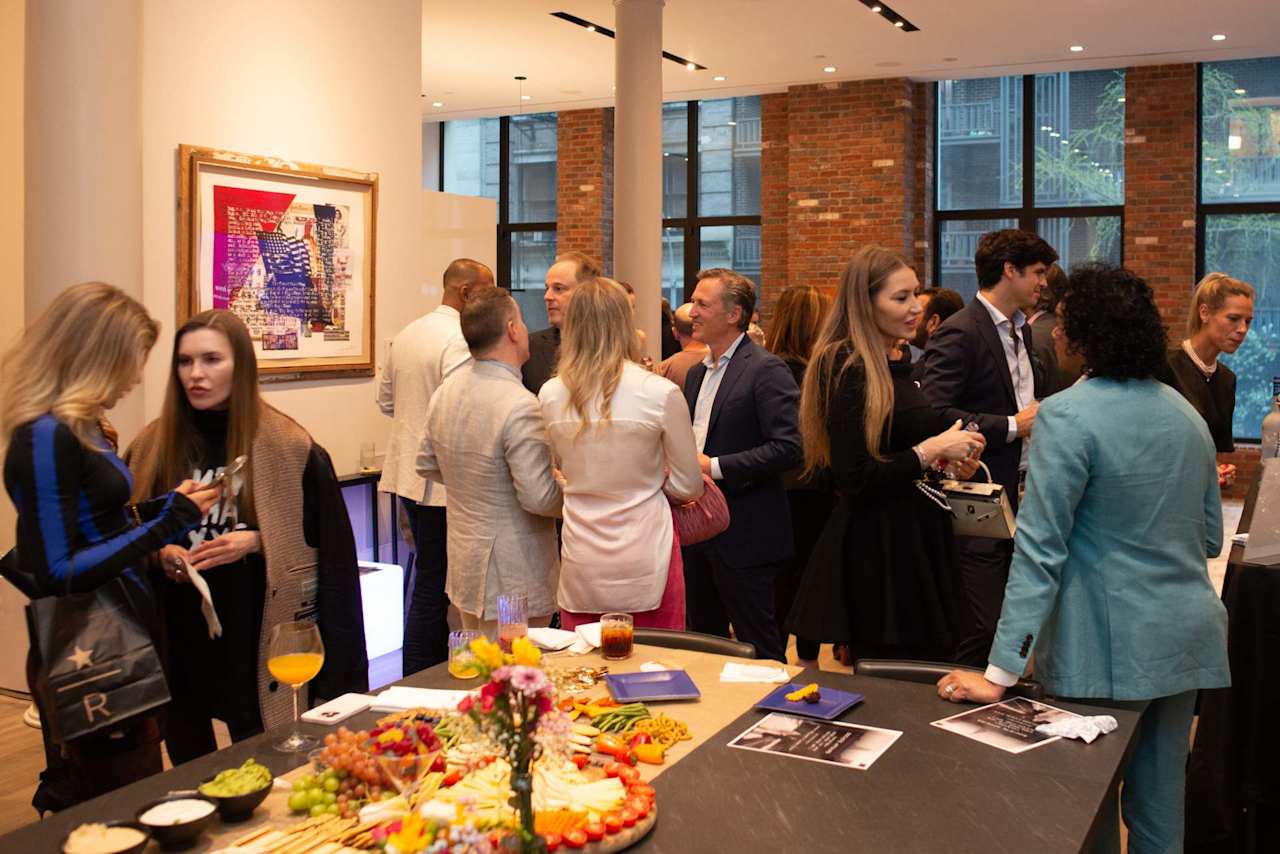 Guests mingle around a buffet at an indoor event in a brick-walled venue.