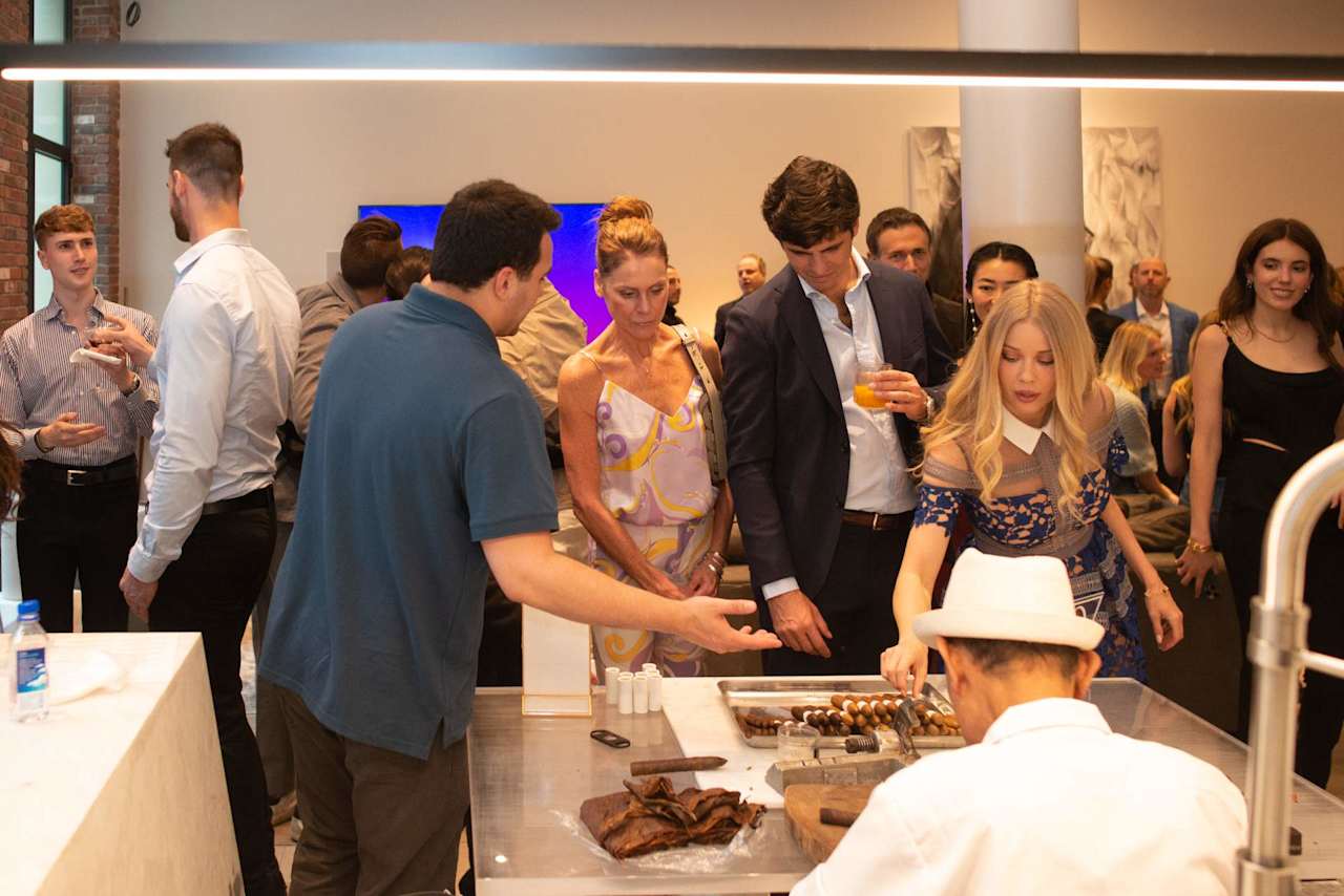 Guests gather around a chef serving food at an indoor event.