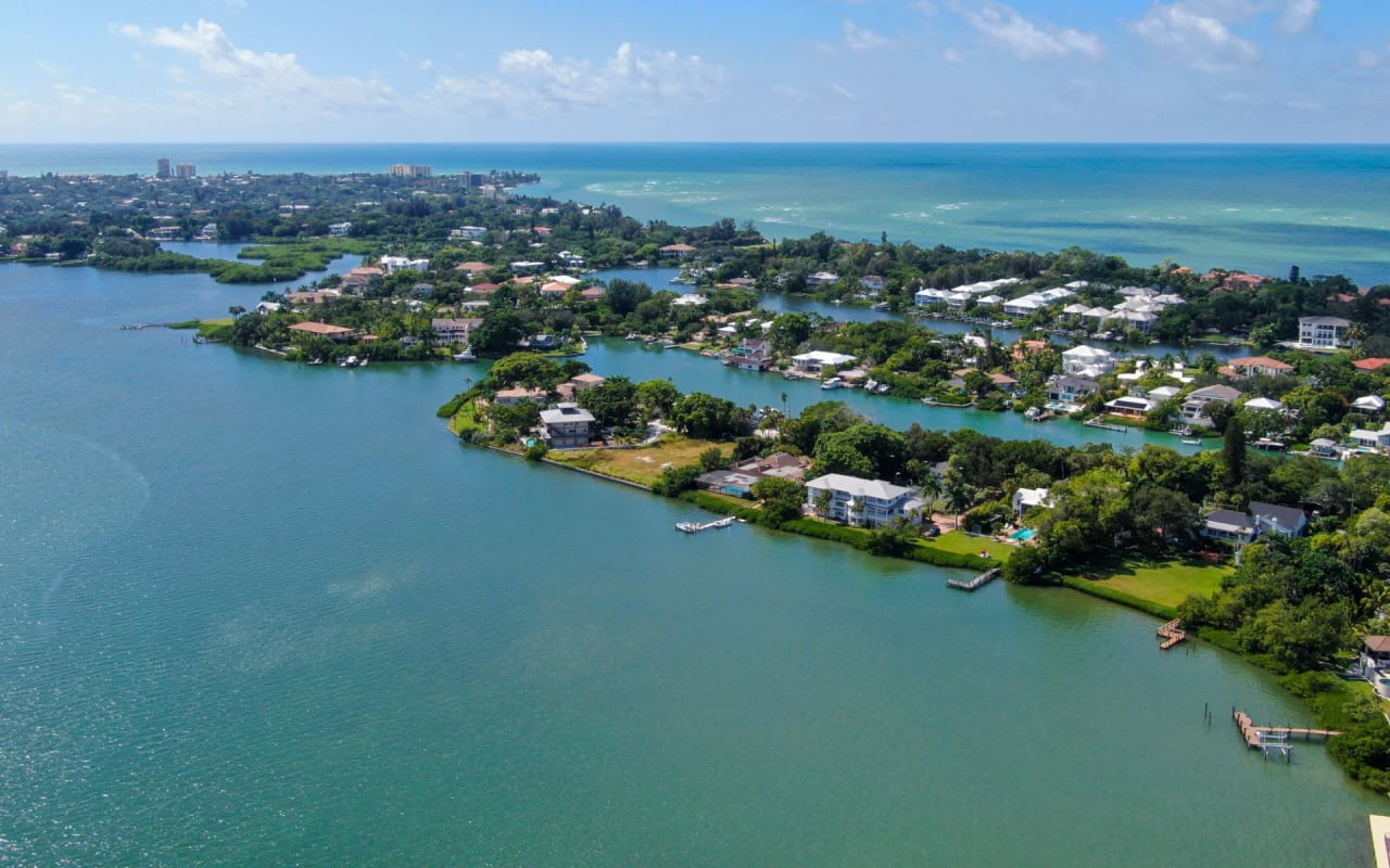 Aerial view of a residential area on water, with houses on stilts and boats in the canals